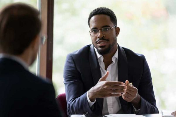 Un homme échange avec un autre homme autour d'une table