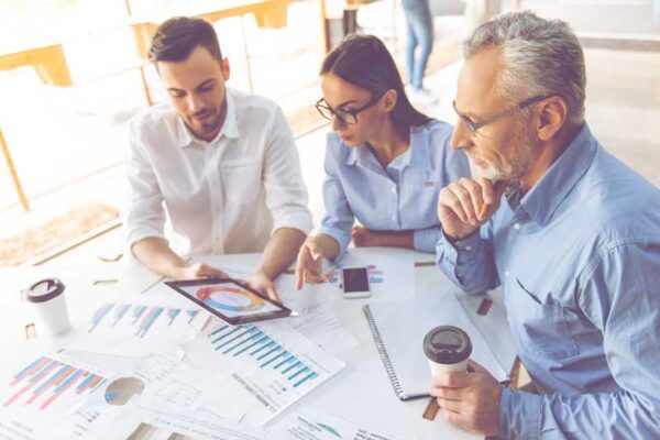 3 personnes travaillent autour d'une table sur des graphiques